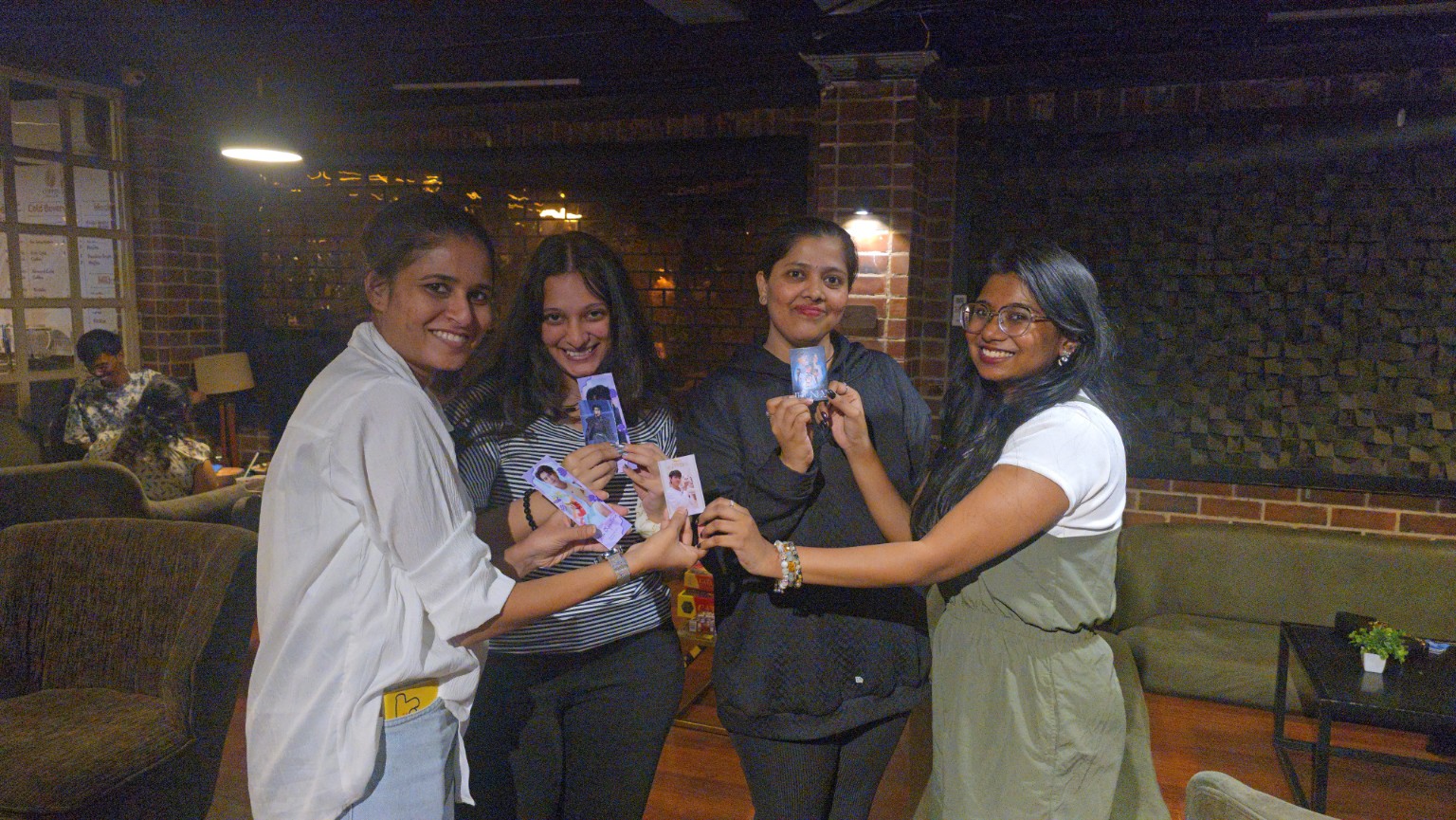 Four attendees holding photocards, smiling together after the murder mystery game